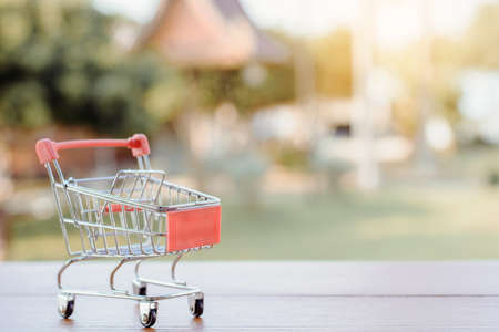 Shopping concept - empty shopping cart or trolley on brown wood table. online shopping consumers can shop from home and delivery service. with copy spaceの写真素材