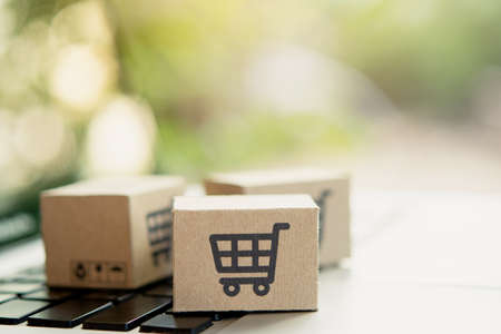 Shopping online. Cardboard box with a shopping cart logo on laptop keyboard. Shopping service on The...