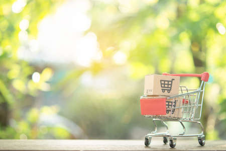 Shopping concept - Shopping cart or trolley and Paper cartons or parcel with a shopping cart logo on...