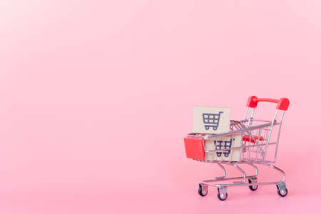 Shopping concept : Cartons or Paper boxes in red shopping cart on pink background. online shopping consumers can shop from home and delivery service. with copy spaceの写真素材