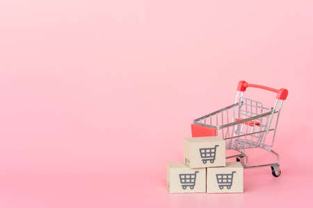 Shopping concept : Cartons or Paper boxes in red shopping cart on pink background. online shopping consumers can shop from home and delivery service. with copy spaceの写真素材