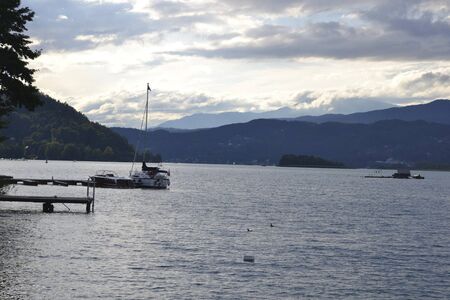 view to a lake at sunset with boats in summerの写真素材