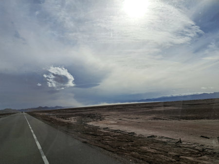 Road in the desert with cloudy blue sky and white clouds in the backgroundの写真素材
