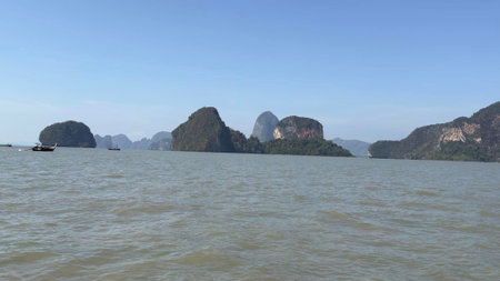 Glistening waves gently lap against rocky shores, while impressive limestone cliffs tower above serene waters, creating a peaceful escape in nature's beauty.の写真素材