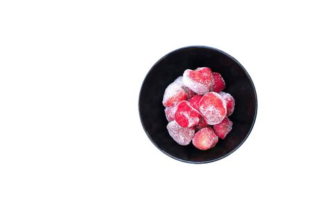 Frozen strawberries in a black bowl on white background and isolated.selective focus.の写真素材