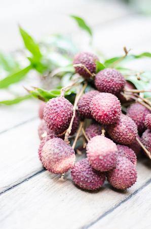 Lychee with leaves on a wooden tableの写真素材