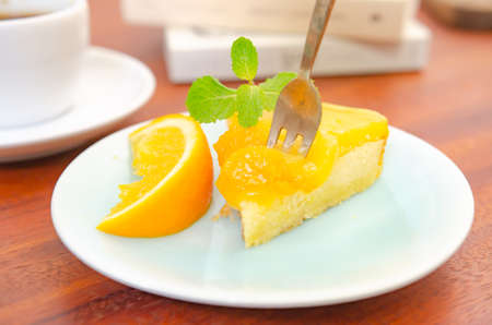 Orange cake decorated with fresh oranges on a wooden table.