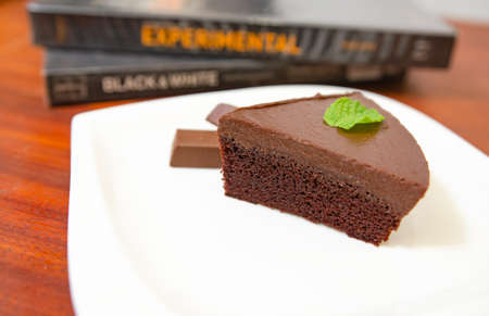 Chocolate cake decorated with chocolate sauce on a wooden table.