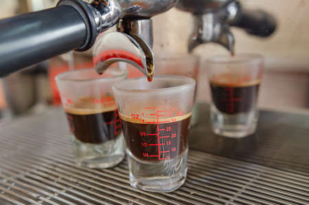 Espresso from a coffee machine pouring into a white cup of coffee.の写真素材