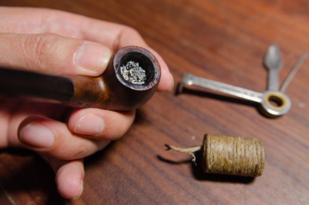 man lighting a tobacco pipe on a wooden table background Soft focusの写真素材