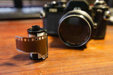 Film camera and 35 mm film roll on wooden tableの写真素材