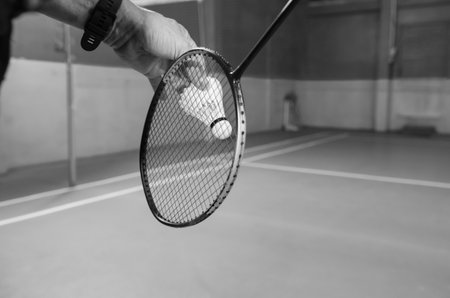 An athlete serving a shuttlecock in a badminton game