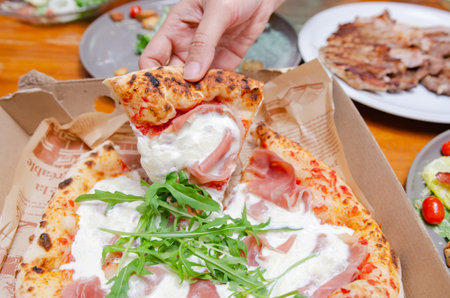 A baker making bread in the kitchenPizza with parma ham Italian style in a paper boxの写真素材