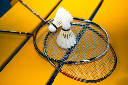 Badminton rackets and white cream badminton shuttlecocks after playing or after games on green floor...