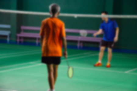 Blurred people playing badminton in green court.の写真素材