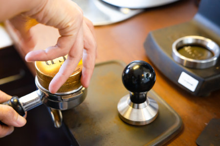 Close-up of hand Barista cafe making coffee with manual presses ground coffee using tamper at the coffee shopの写真素材