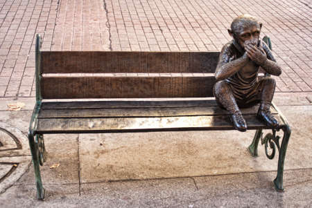 Sculpture of a monkey sitting on a bench in the parkの写真素材