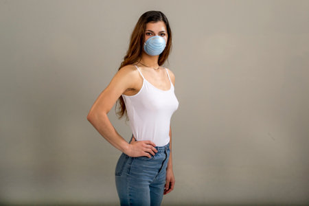Thin, busty, brunette wearing a strappy white t-shirt and faded blue jeans wearing a round, blue,...
