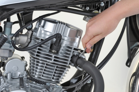mechanic tightening the exhaust on a motorcycle engine