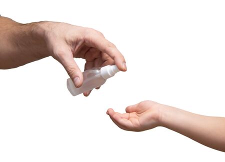 man put antibacterial spray on the hands of a child on white backgroundの写真素材
