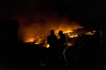 Silhouette of a man with a motocycle rider on a fire backgroundのeditorial素材