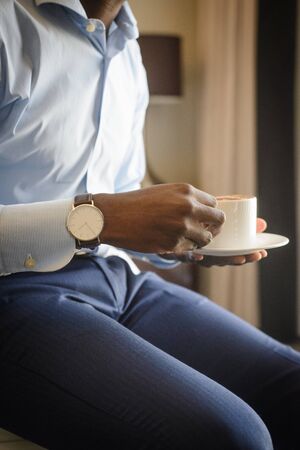 Businessman with watch on his wrist drinking morning coffeeの写真素材