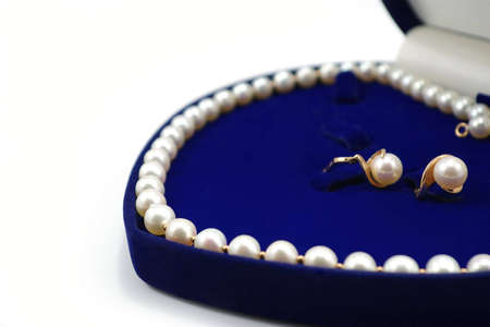 pearl necklace and two earrings in blue heart-shaped box on white backgroundの写真素材