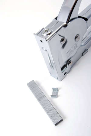 metallic industrial stapler with staples on white background