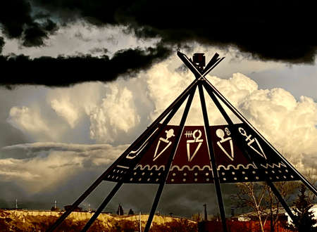 Steel teepee sculpture at the gates of Calgary Stampede with heavy storm clouds in the distance.