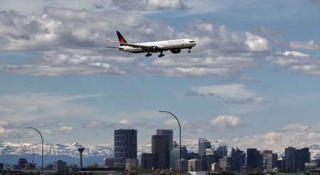 A passenger jet on approach at Calgary International Airport with the Calgary skyline and the Rocky...