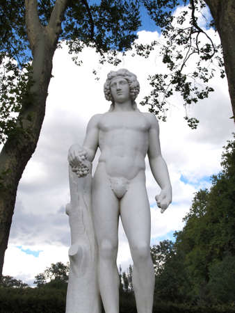Statue of man hold a grape for Decorate Gardens at Versailles in France against blue sky with cloud and Treesの写真素材