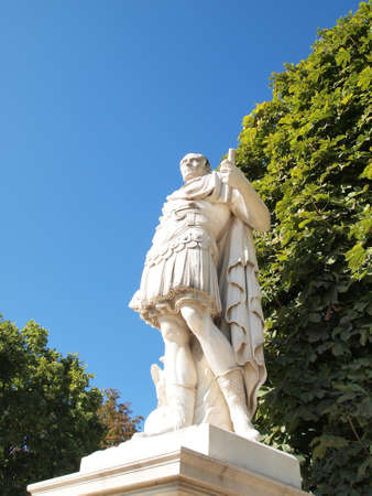 Statue of old man hold a Paper for Decorate Gardens at Paris in France against blue sky with cloud and Treesの写真素材