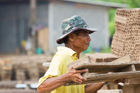 man laborer lifts the wood of Production of bricks in thailandの写真素材