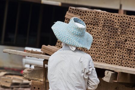 Woman laborer is dislocating a brick of Production of bricks in thailand