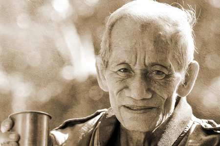 an aged cheerful old man holding a cup of coffeeの写真素材