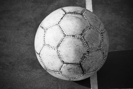 Old used football or soccer ball on cracked asphaltの写真素材