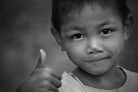 Portrait of beautiful little boy giving you thumbs up over white backgroundの写真素材