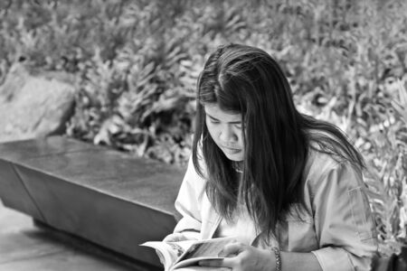 Woman reading book in park outdoors