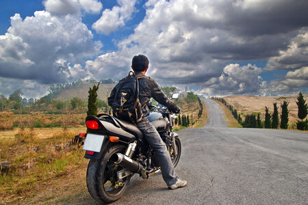 Low angle view of man riding bike against clear skyの写真素材