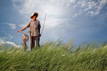 man riding  bike.on green field and blue skyの写真素材