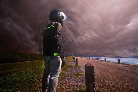 Biker standing with its motorbike on stormの写真素材