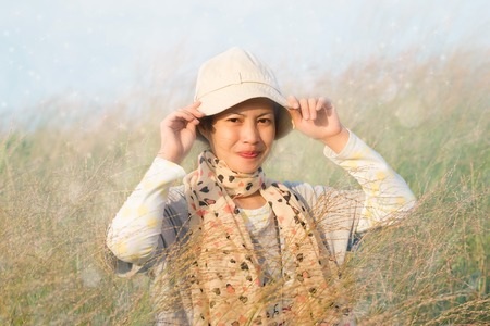 Young woman is standing in meadow with raised arms enjoying sunlightの写真素材