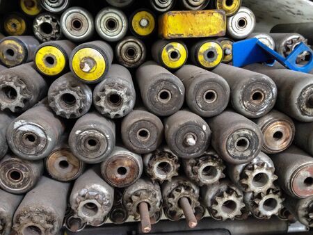Stack of old rusty conveyor rollers