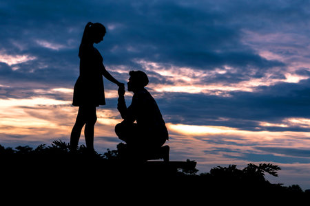 Silhouette couple in love Men ask for married and kissing at the hands of women on beautiful sunset background , valentine conceptの写真素材