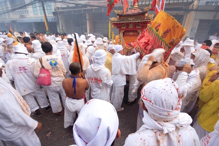 Devotees of a Taoist shrine carry a God idol on a palanquin while participating in a street...