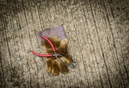 Still life with old locking plier and old glove on grunge background