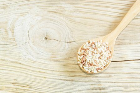 Brown rice on wooden spoon on wooden white  background. Product of Thailand, Asia.の写真素材