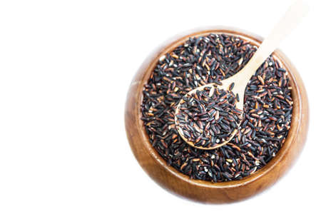 Black rice on wooden spoon in a wooden bowl isolated on white  background. Product of Thailand, Asia.の写真素材