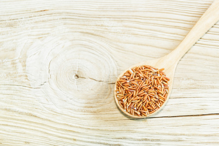 Sangyod brown GI rice on wooden spoon on wooden  background. Product of Thailand, Asia.の写真素材