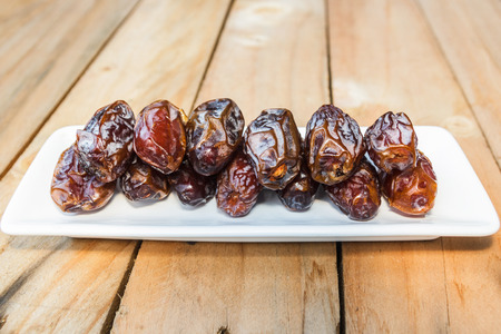 Dates fruit in a wooden bowl closeup on wooden backgroundの写真素材